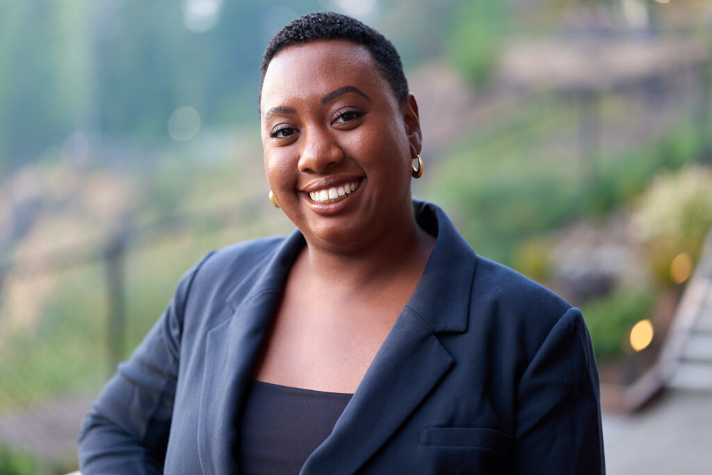 Shaterra in a navy blazer, smiling in front of a blurred background.