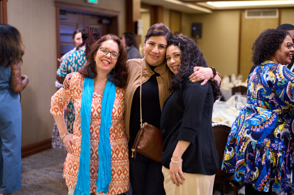 Three women embracing and smiling celebratorily 