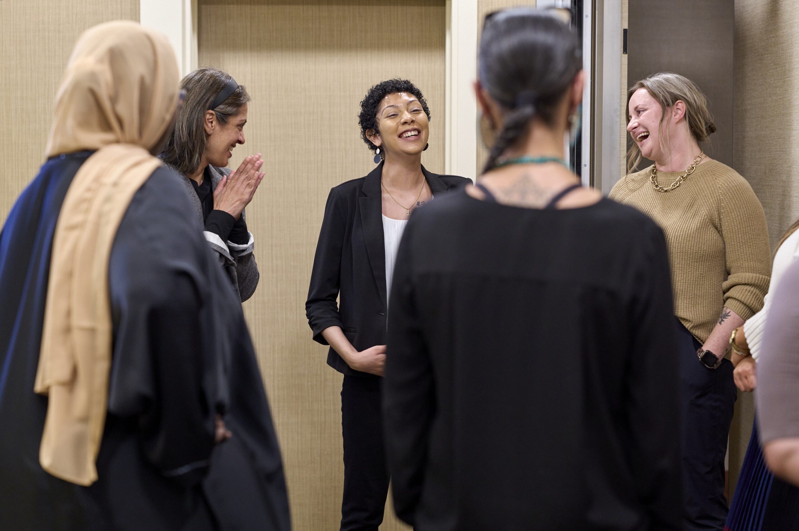 A group of women smile and look at each other