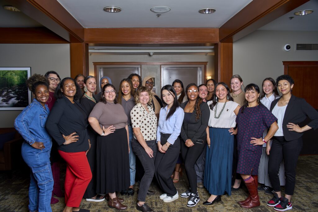 A group of leaders stand together facing the camera. They represent many races and gender expressions.